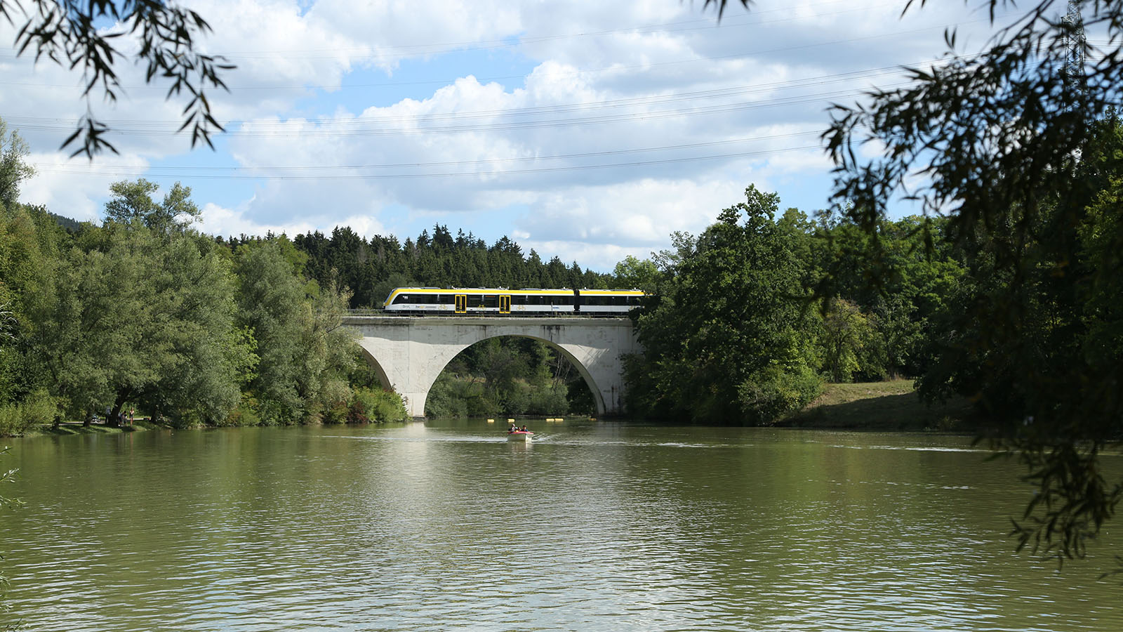 Der Freizeitexpress „Schieferbahn“ fährt auf einer Zugbrücke mit Seelandschaft