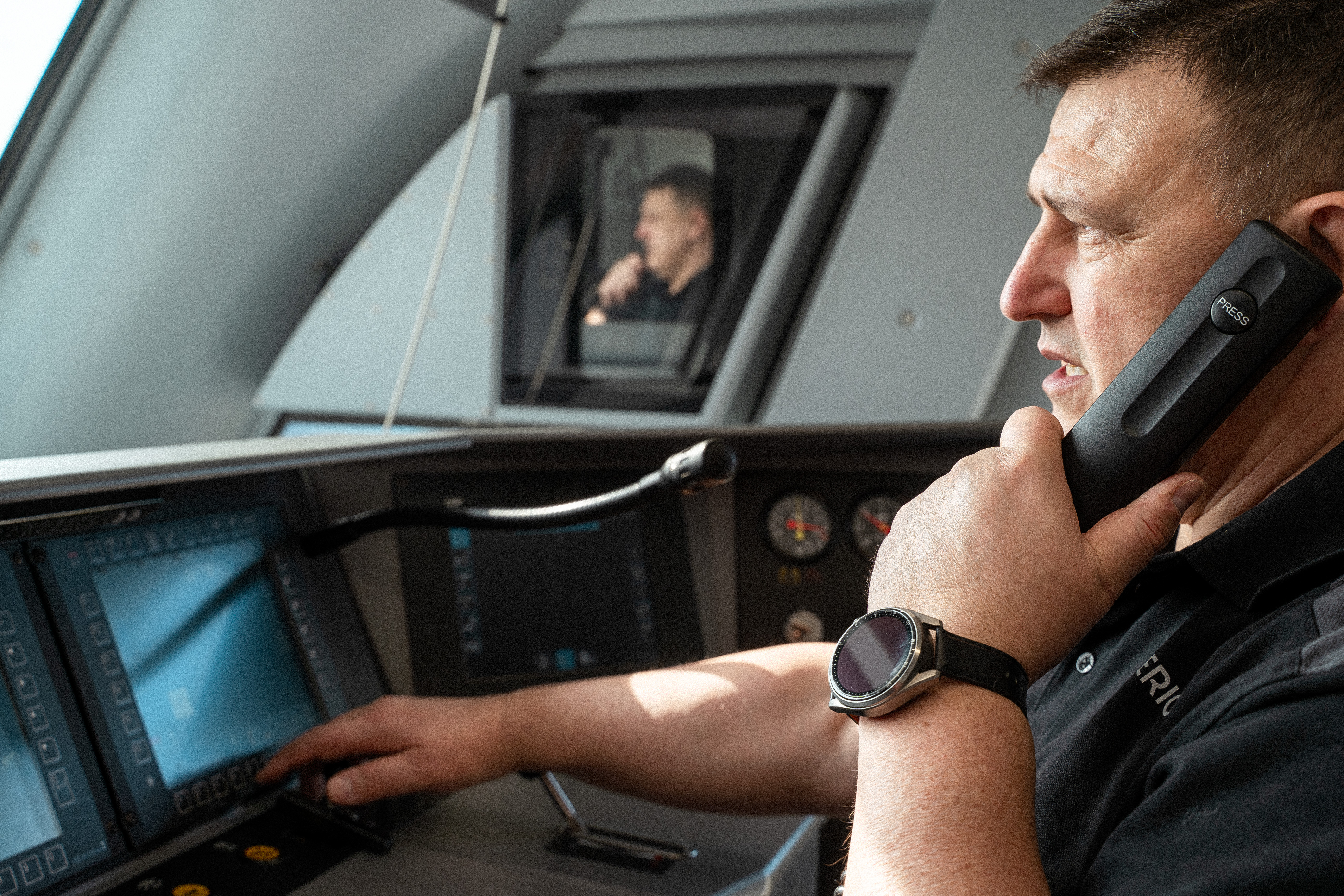 Ein Triebfahrzeugführer im Führerstand eines Zuges spricht in einen Telefonhörer. 