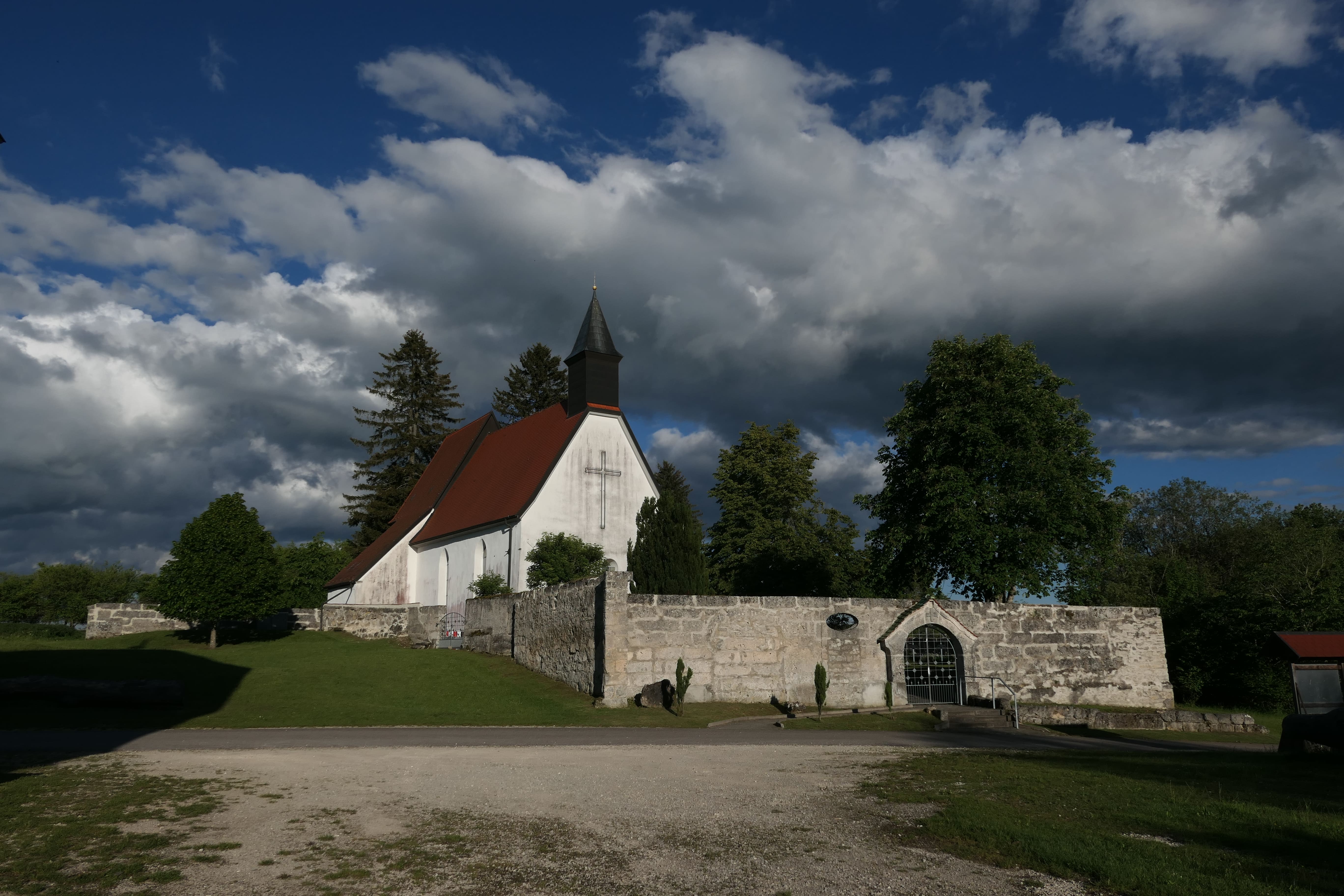 Das verlassene Dorf Gruorn mit Friedhof und Kirche vor einem bewölkten Himmel