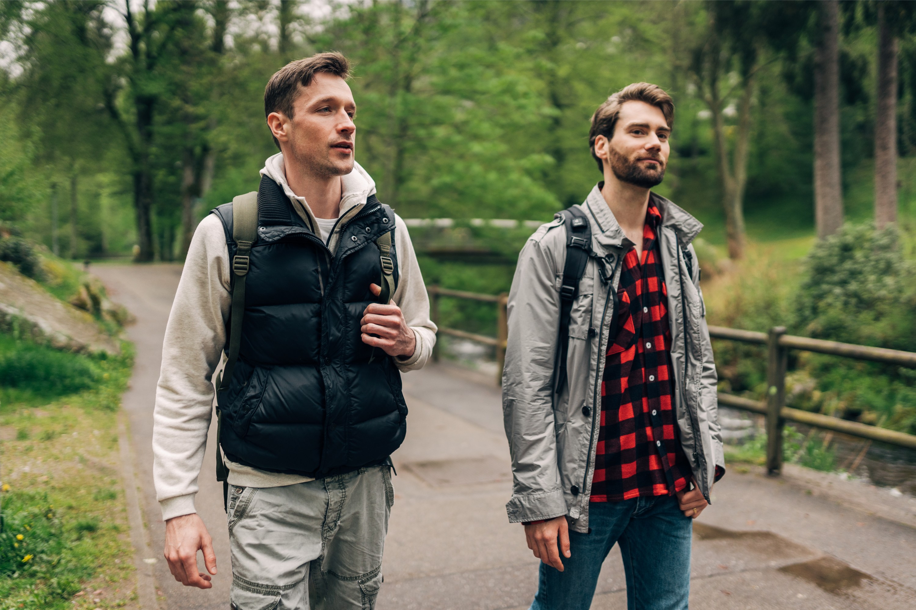 Zwei junge Männer in Wanderkleidung wandern durch den Wald.