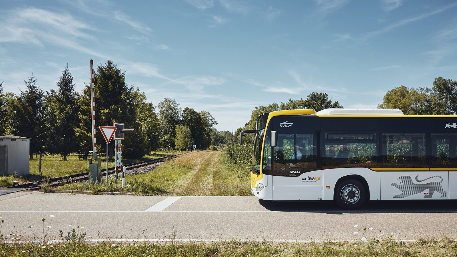 Ein bwregiobus steht vor einem Bahnübergang