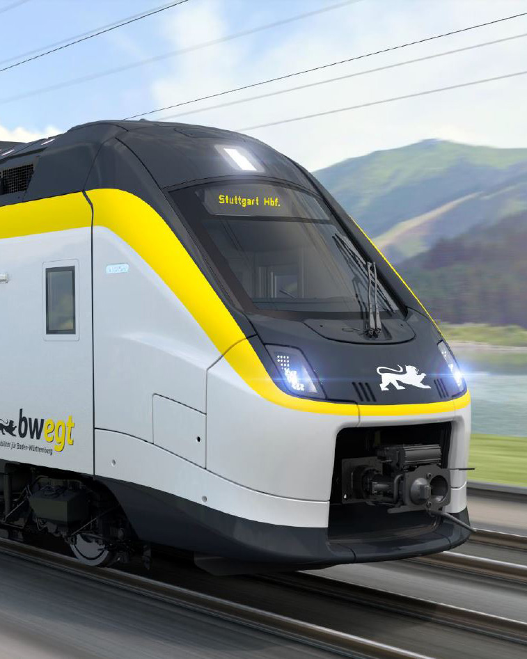 Ein Coradia Max Zug fährt eine grüne Landschaft entlang