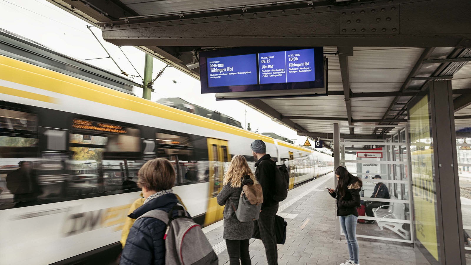 Mehrere Personen warten am Bahnhof und ein bwegt-Zug fährt ein